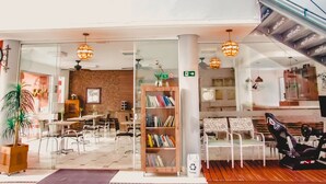 A modern indoor space with a glass partition, wooden bookshelves, and seating areas. - Serra Negra Pousada Spa by Easy Hoteis (Guarapari)
