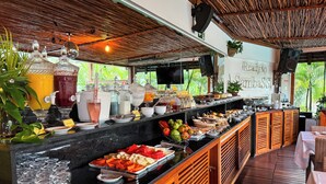 A buffet setup with various food items and drinks, a wooden counter, and a sign reading "Ready to Embass". - Pousada Sambass (Cairu)