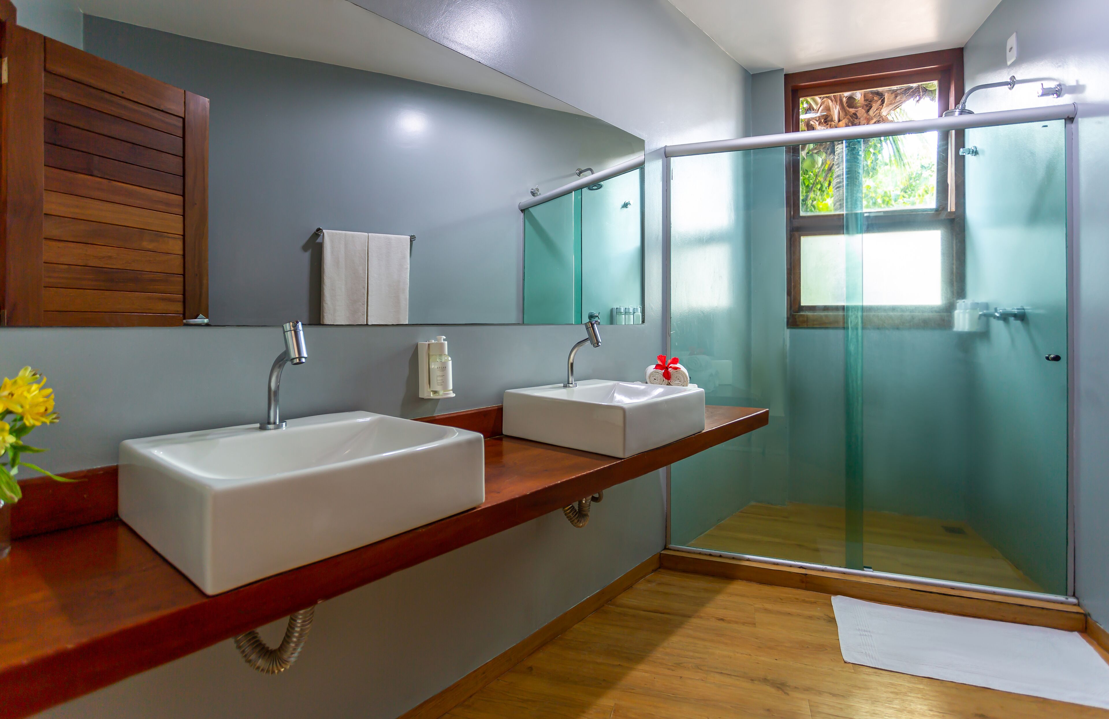 A bathroom with two sinks, a shower, and a large mirror.