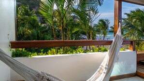 A hammock on a balcony with a view of a beach and palm trees. - Pousada Sambass (Cairu)
