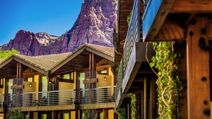 A multi-story building with balconies, wooden architecture, and a mountain backdrop. - Desert Pearl Inn (Springdale)