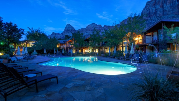 A pool area with lounge chairs and a mountain backdrop. - Desert Pearl Inn (Springdale)