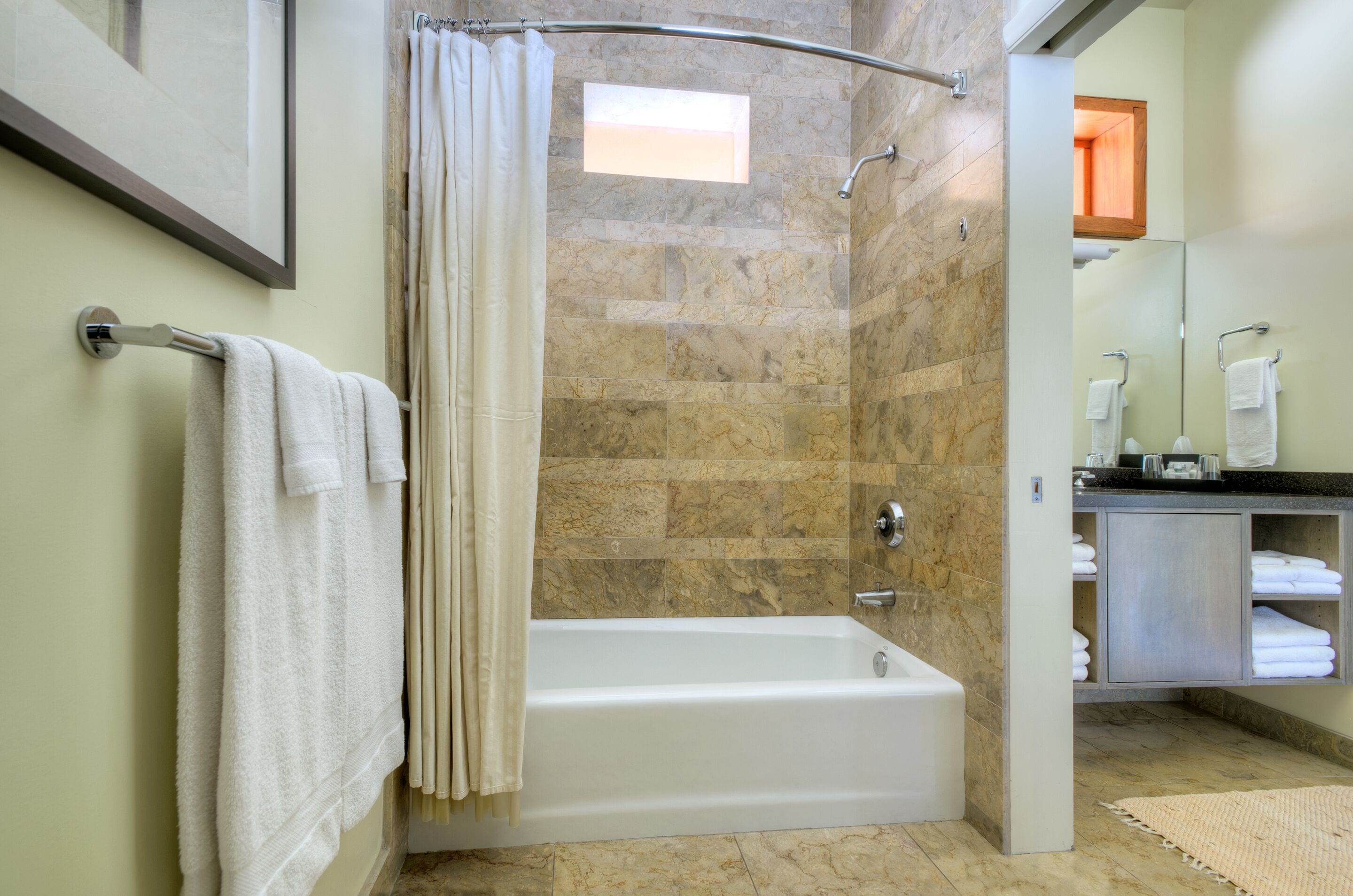A modern bathroom with a bathtub, shower curtain, and a vanity with towels.