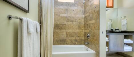 A modern bathroom with a bathtub, shower curtain, and a vanity with towels.