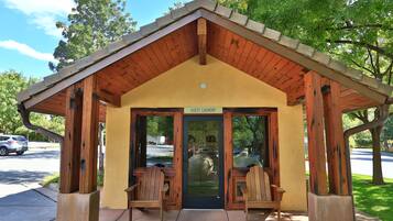 A guest laundry facility with a wooden structure, two wooden chairs, and a door with a sign above it.