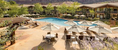 Una piscina al aire libre, sombrillas, sillones reclinables de piscina