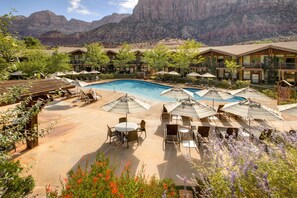 A resort with a pool area, outdoor seating, and mountain views.