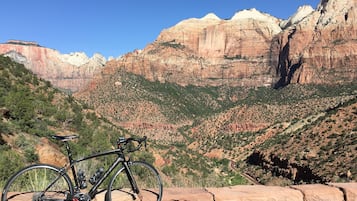 A bicycle parked on a rocky ledge overlooking a canyon with a clear sky.