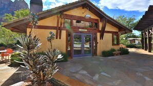 A lodge with a stone patio, a registration sign, and a mountain backdrop. - Desert Pearl Inn (Springdale)