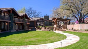 A modern building with a stone pathway, a covered patio, and a well-maintained lawn. - Desert Pearl Inn (Springdale)