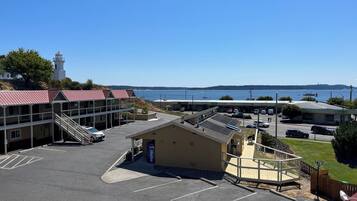 A parking lot with a building that has a red roof and a Pepsi sign. There is a lighthouse in the background and a view of the water.