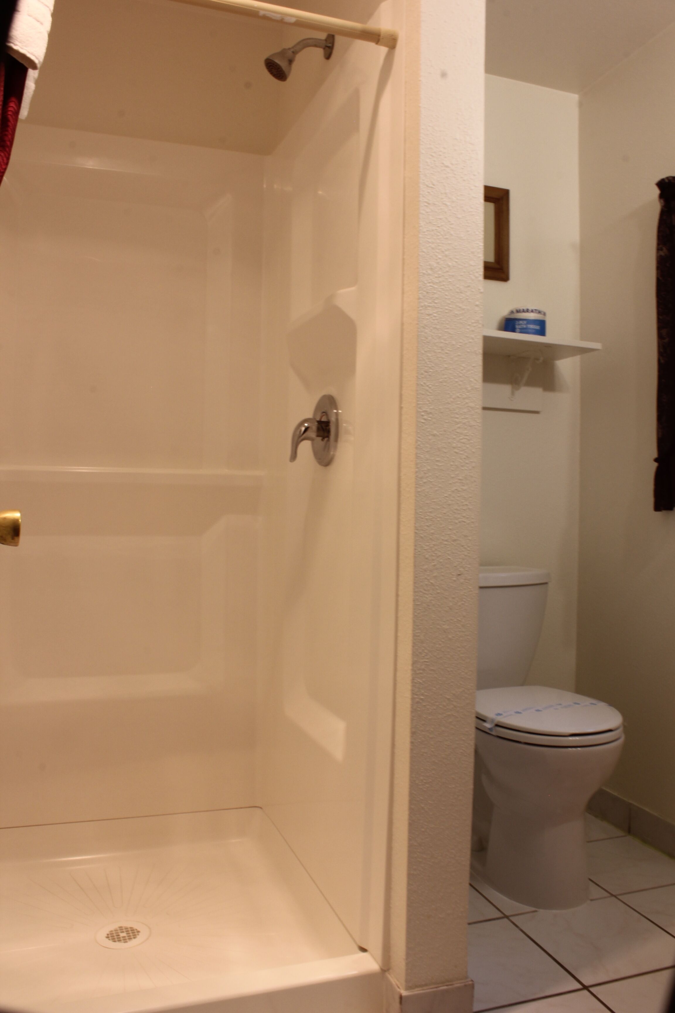 Ein Badezimmer mit Dusche, Toilette und Handtuchhalter.