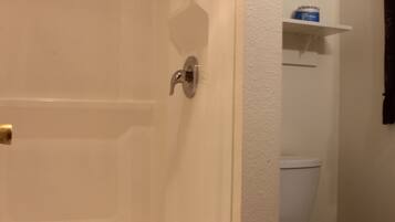 Ein Badezimmer mit Dusche, Toilette und Handtuchhalter.
