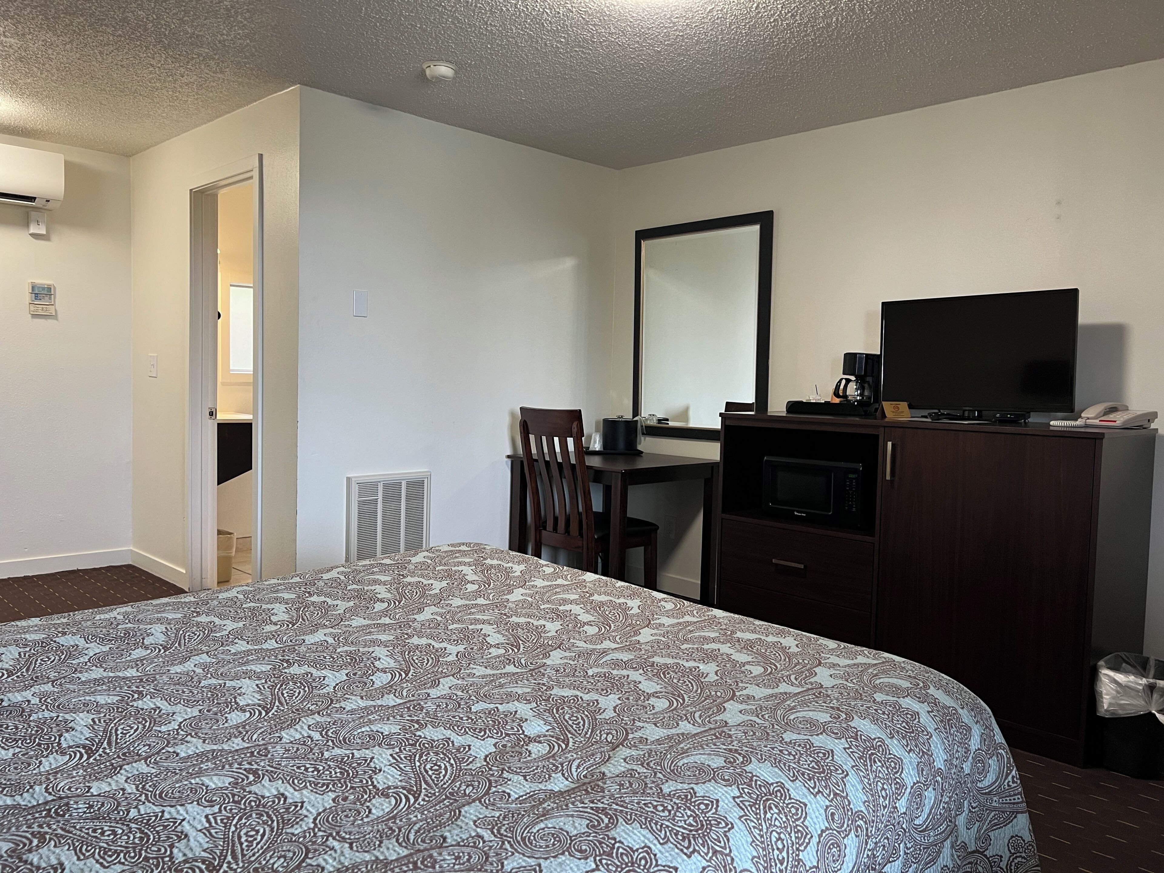 Une chambre d’hôtel avec un grand lit, un bureau avec une télévision, un four à micro-ondes et une chaise.