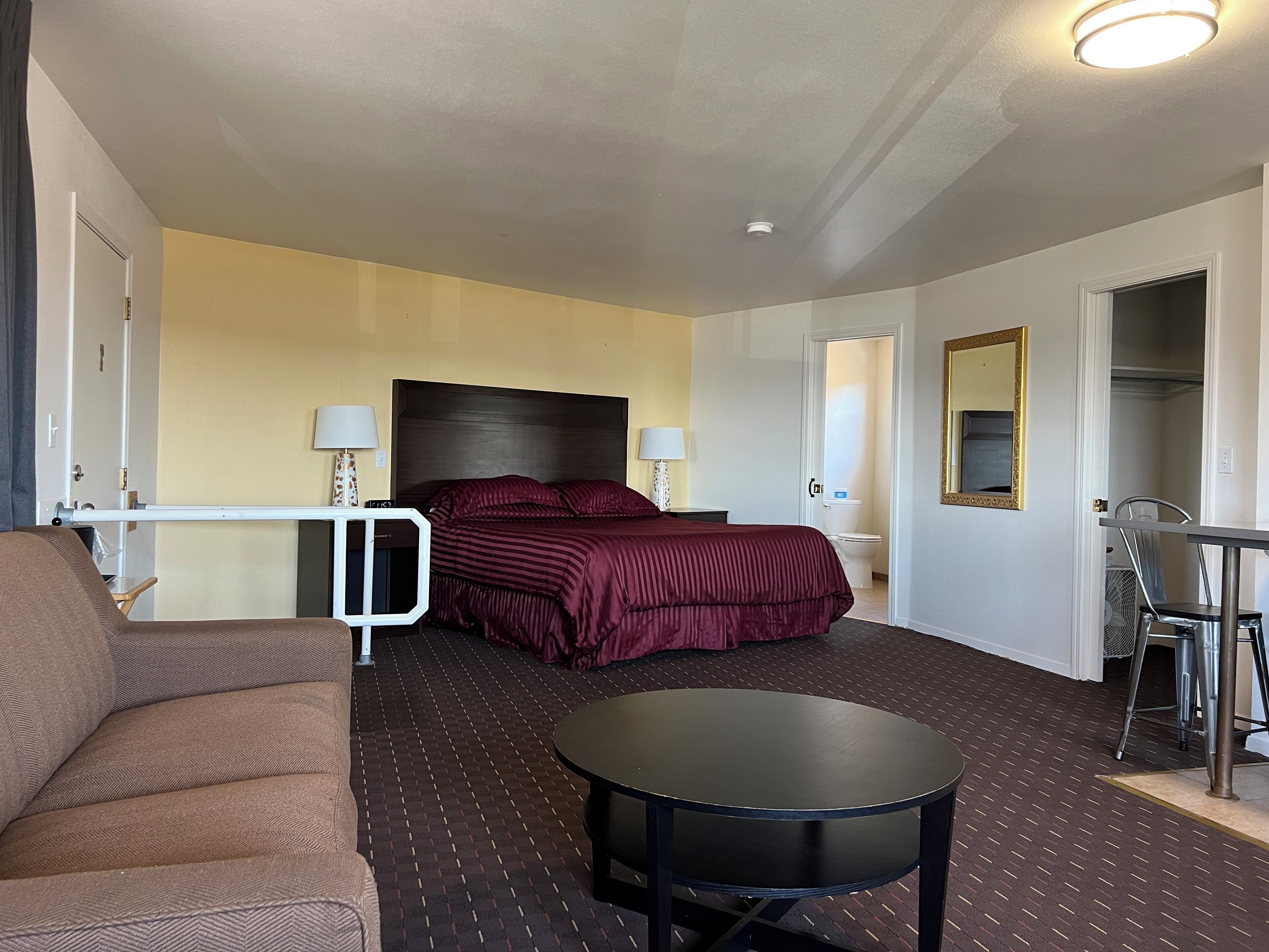 A hotel room with a bed, a round table, a sofa, and a mirror.
