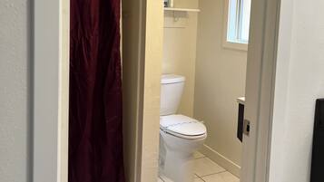 Ein Badezimmer mit Toilette, Duschvorhang und Fenster.