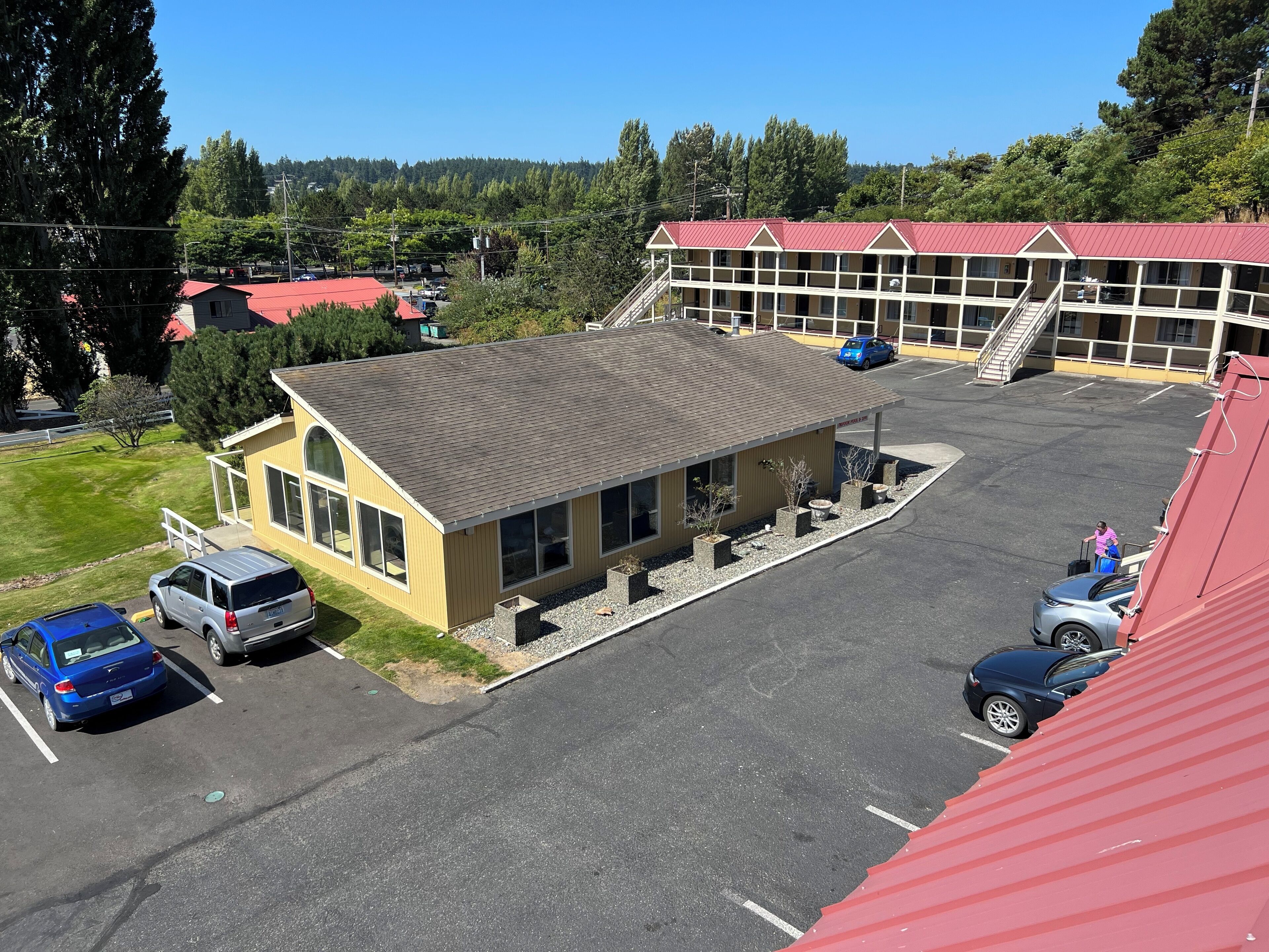 A building with a red roof, a parking lot, and a small building with large windows.