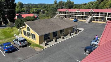 A building with a red roof, a parking lot, and a small building with large windows.