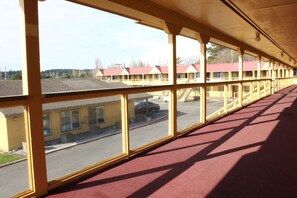 A motel with a row of rooms, large windows, and a covered walkway.