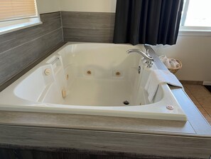 A modern bathroom with a freestanding bathtub, a towel rack, and a wicker basket.