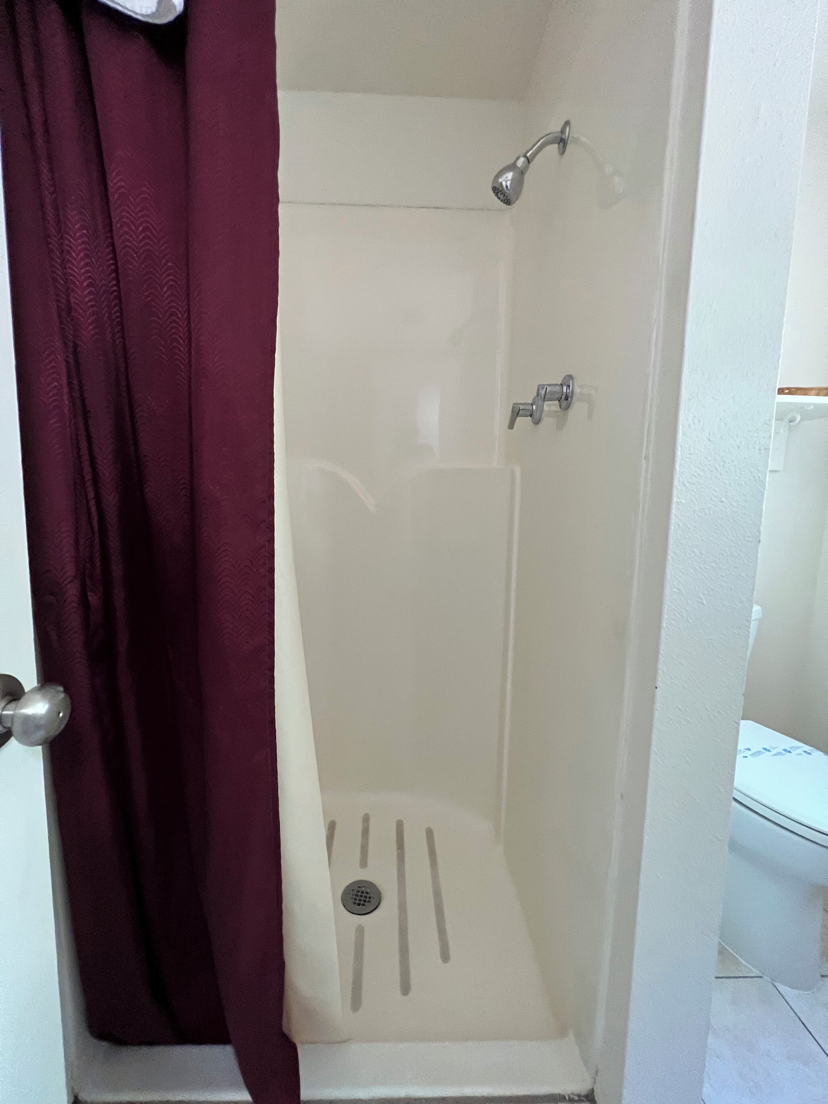 A small, enclosed shower area with a showerhead and a drain.