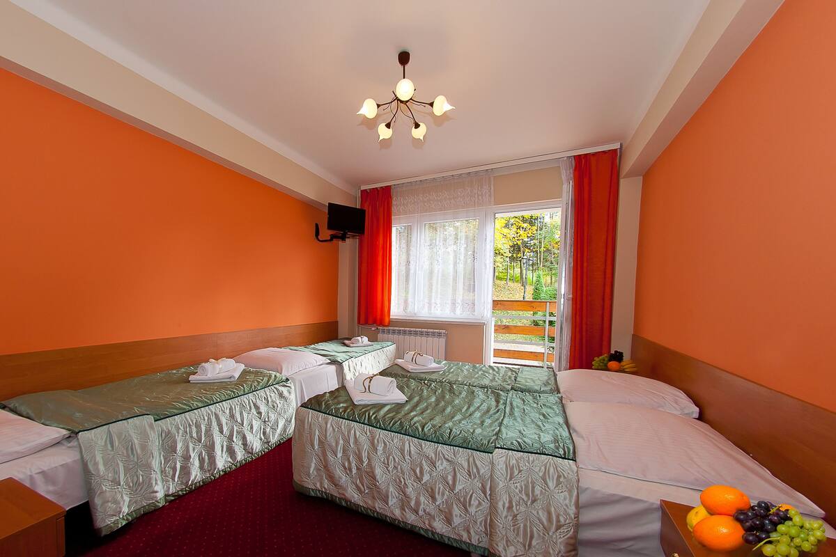 Hotellihuone, jossa on kaksi sänkyä, ikkuna, josta on näkymä ulos, ja hedelmäkori yöpöydällä.