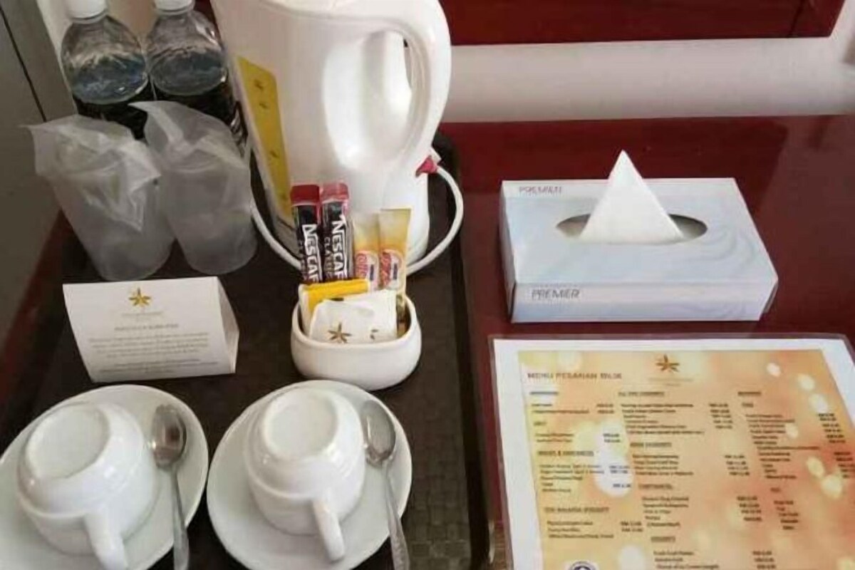 Preparación del desayuno en una habitación de hotel, con un menú, una cafetera, bolsitas de té y una caja de pañuelos.