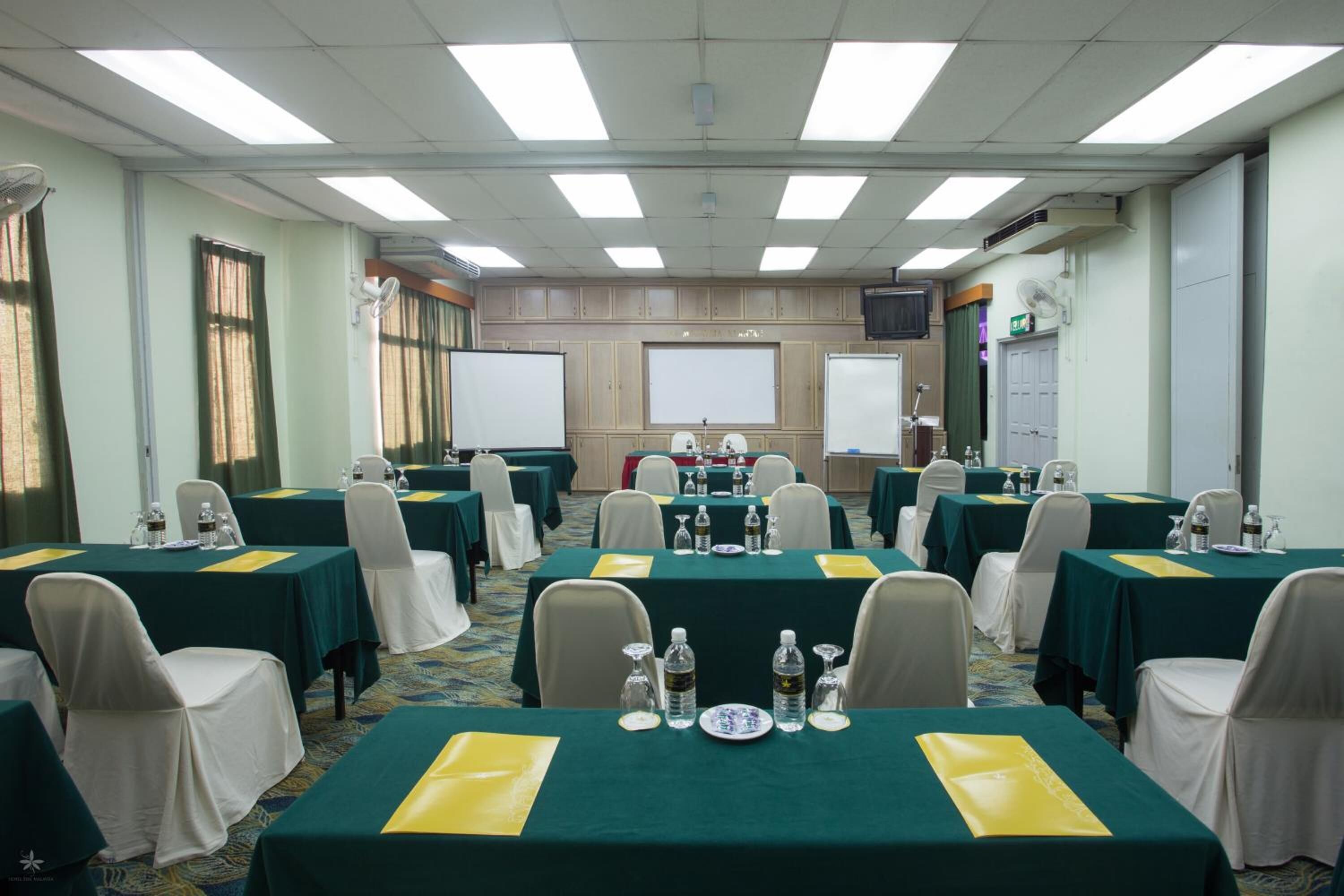 A conference room with multiple tables, chairs, and a projector screen.