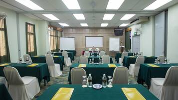 A conference room with multiple tables, chairs, and a projector screen.