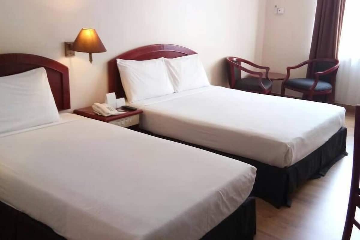 A hotel room with two beds, a bedside lamp, a chair, an air conditioning unit, and a framed picture on the wall.