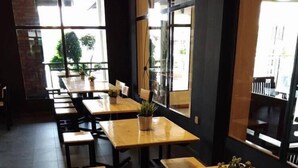 A restaurant interior with wooden tables and chairs, potted plants, and large windows allowing natural light. - Hotel Seri Malaysia Kuantan (Kuantan)