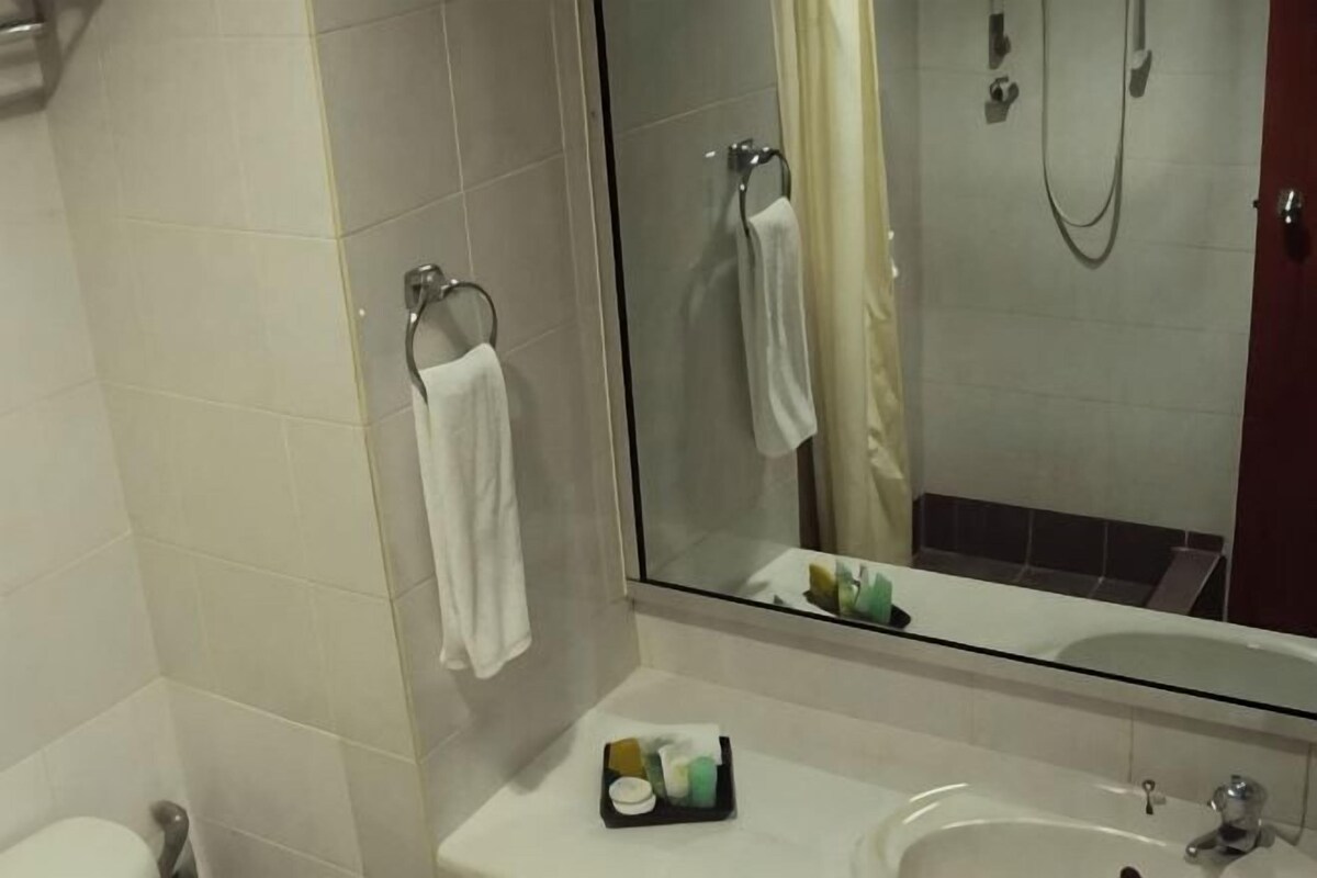 A bathroom with a toilet, a sink, a glass shower enclosure, and a mirror.