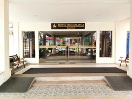 La entrada del Hotel Seri Malaysia en Kuantan, con fachada de vidrio transparente, un cartel y una serie de escalones que conducen a la entrada.