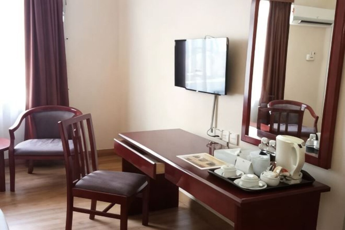 Habitación de hotel con escritorio, silla, televisor y espejo.