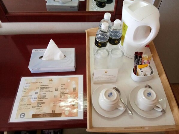 Una bandeja con tetera, tazas, aderezos, un menú y una caja de pañuelos.