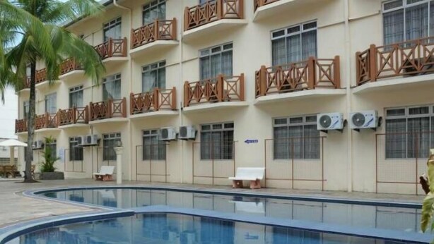 A hotel with a swimming pool, multiple balconies with wooden railings, and air conditioning units on the exterior walls. - Hotel Seri Malaysia Kuantan (Kuantan)
