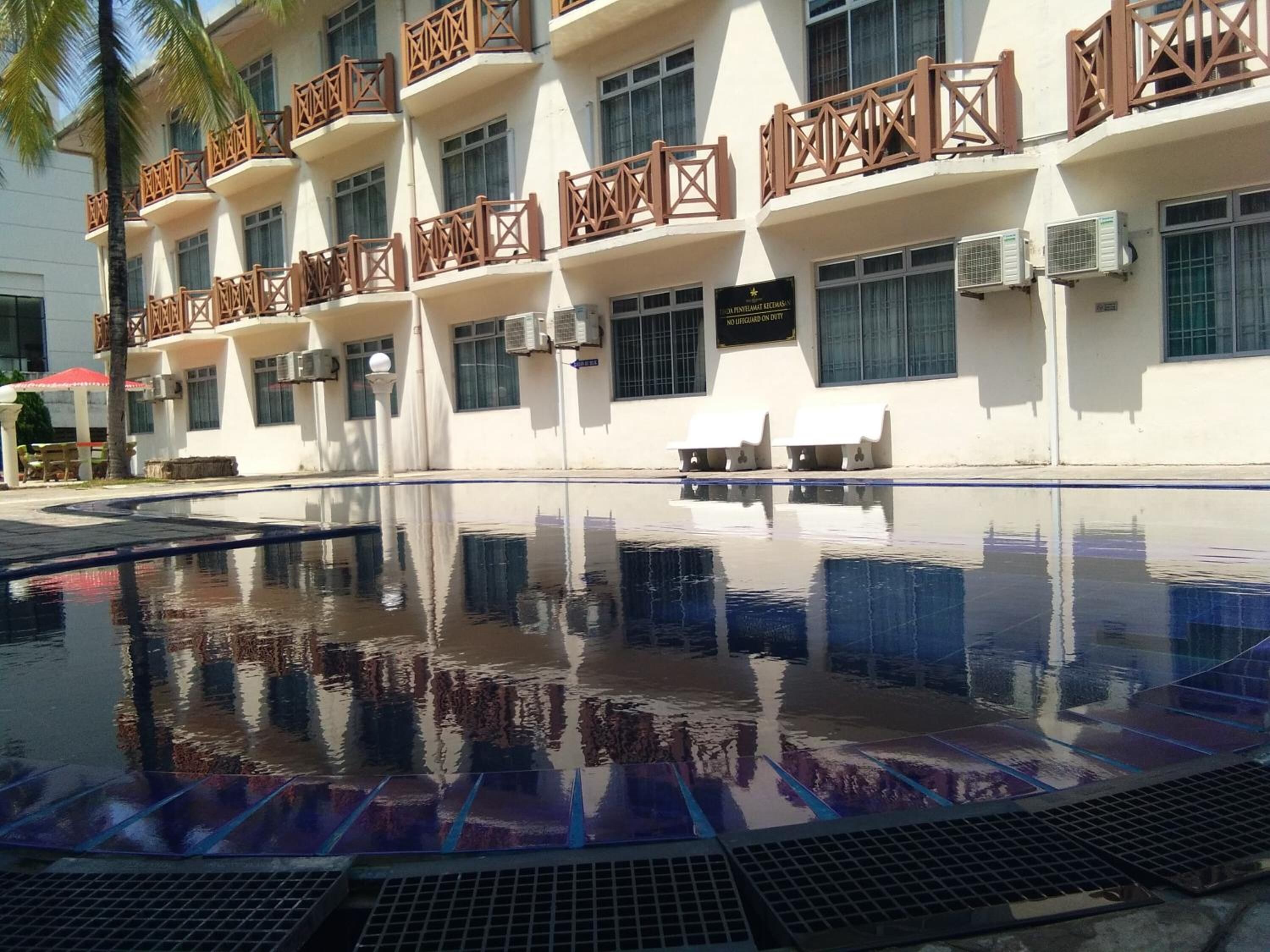 A hotel with a swimming pool, multiple balconies, and air conditioning units.