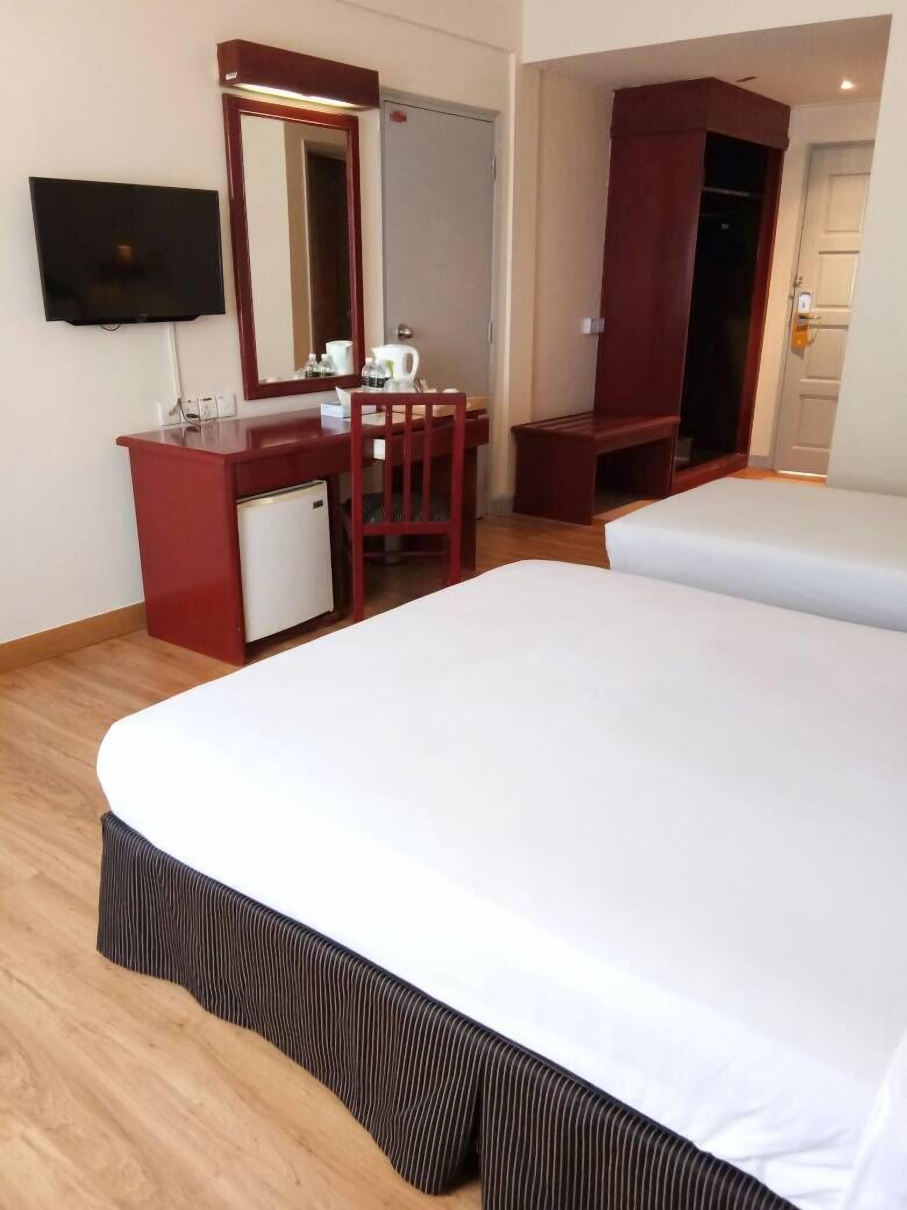 A hotel room with a bed, a desk with a mirror, a television, and a wardrobe.
