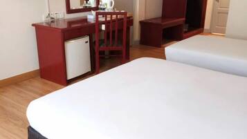 A hotel room with a bed, a desk with a mirror, a television, and a wardrobe.