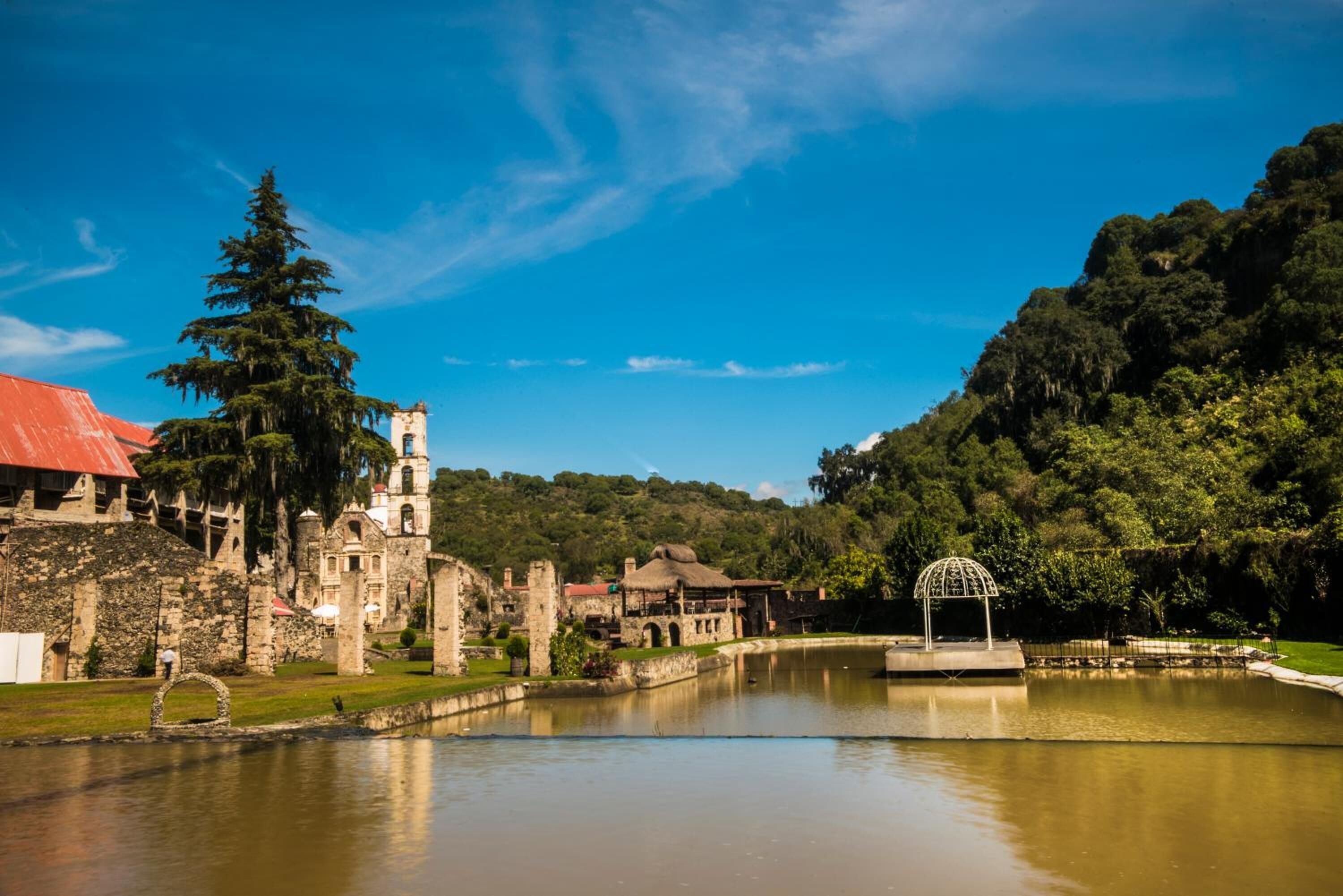 A historic site with ruins, a pond, and a gazebo.