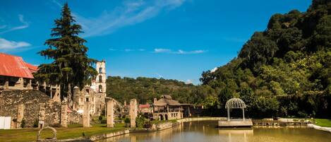 A historic site with ruins, a pond, and a gazebo.