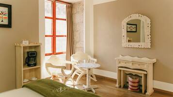 Une pièce comprenant un lit, une chaise, une petite table, une machine à café, un miroir et une fenêtre avec des rideaux.