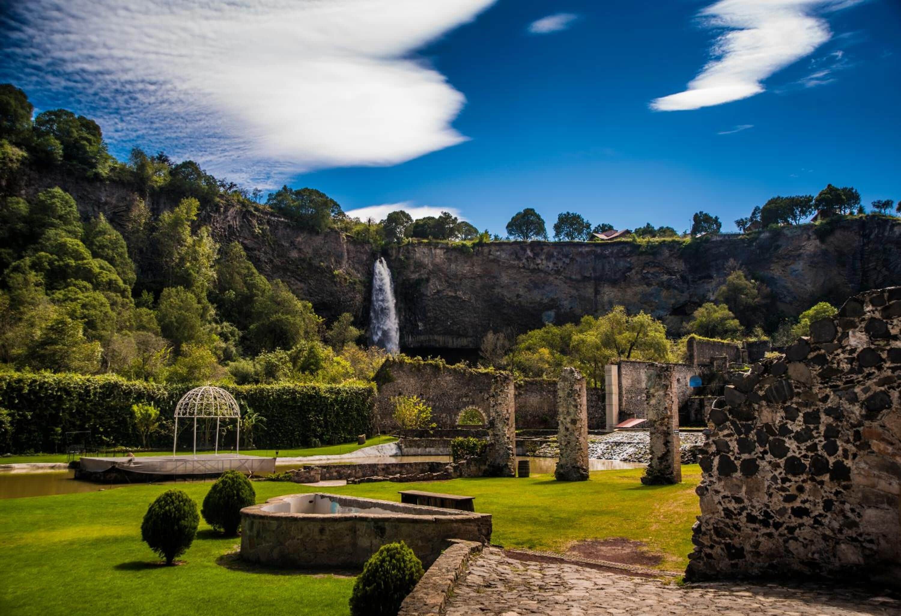 Un sitio histórico con ruinas, una cascada y un jardín bien cuidado.
