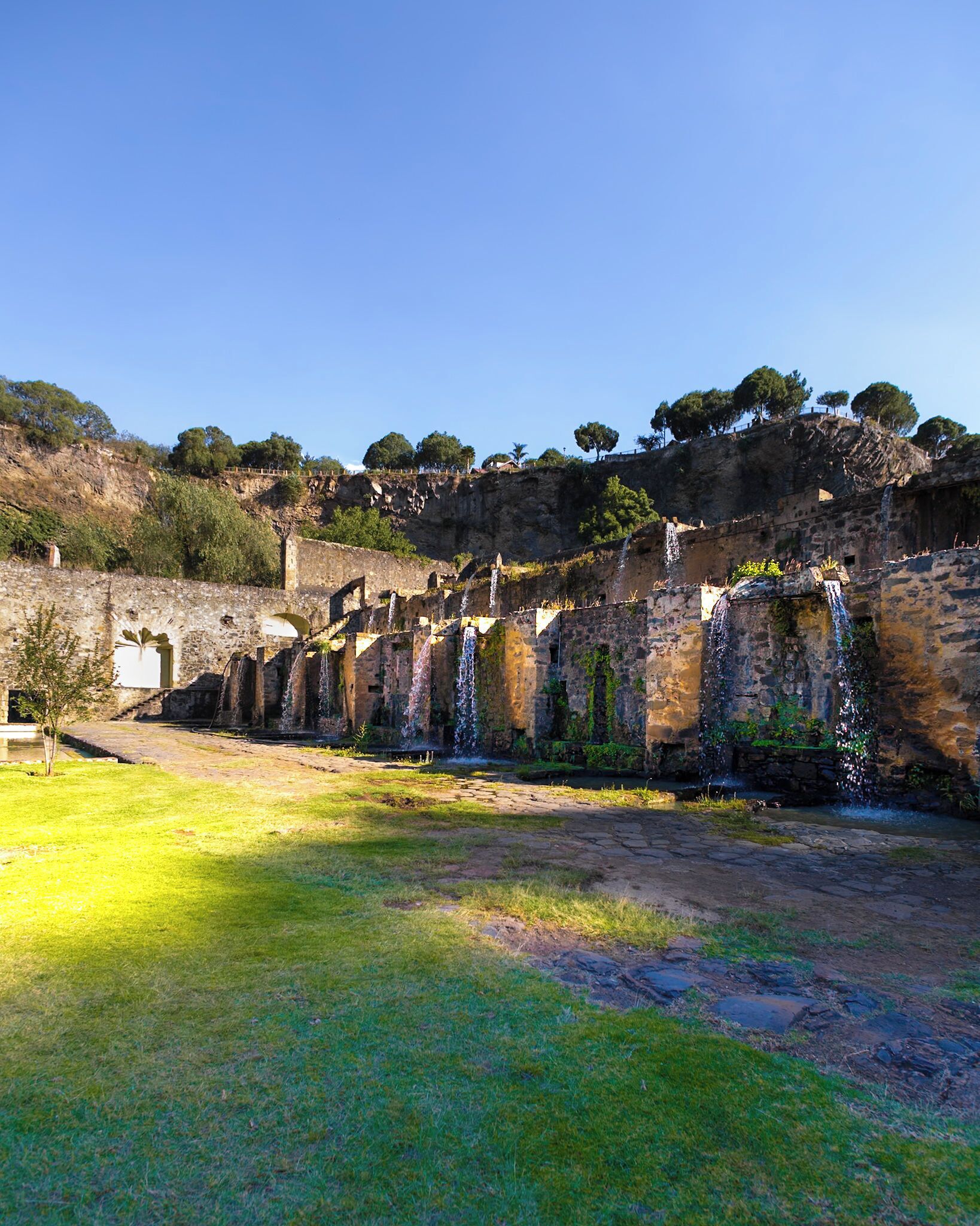 Una antigua estructura de piedra con arcos y una cascada.