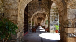 A stone corridor with arches, potted plants, and a lantern. - Hacienda Santa Maria Regla (San Miguel Regla)