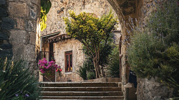 An arched stone structure with steps leading to a building, surrounded by greenery and a cobblestone path. - Hacienda Santa Maria Regla (San Miguel Regla)