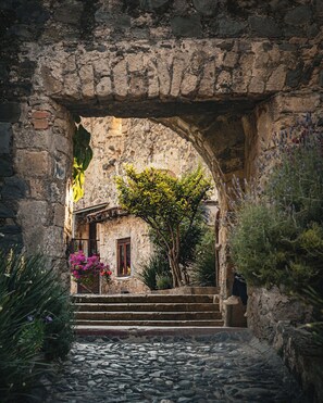 An arched stone structure with steps leading to a building, surrounded by greenery and a cobblestone path. - Hacienda Santa Maria Regla (San Miguel Regla)