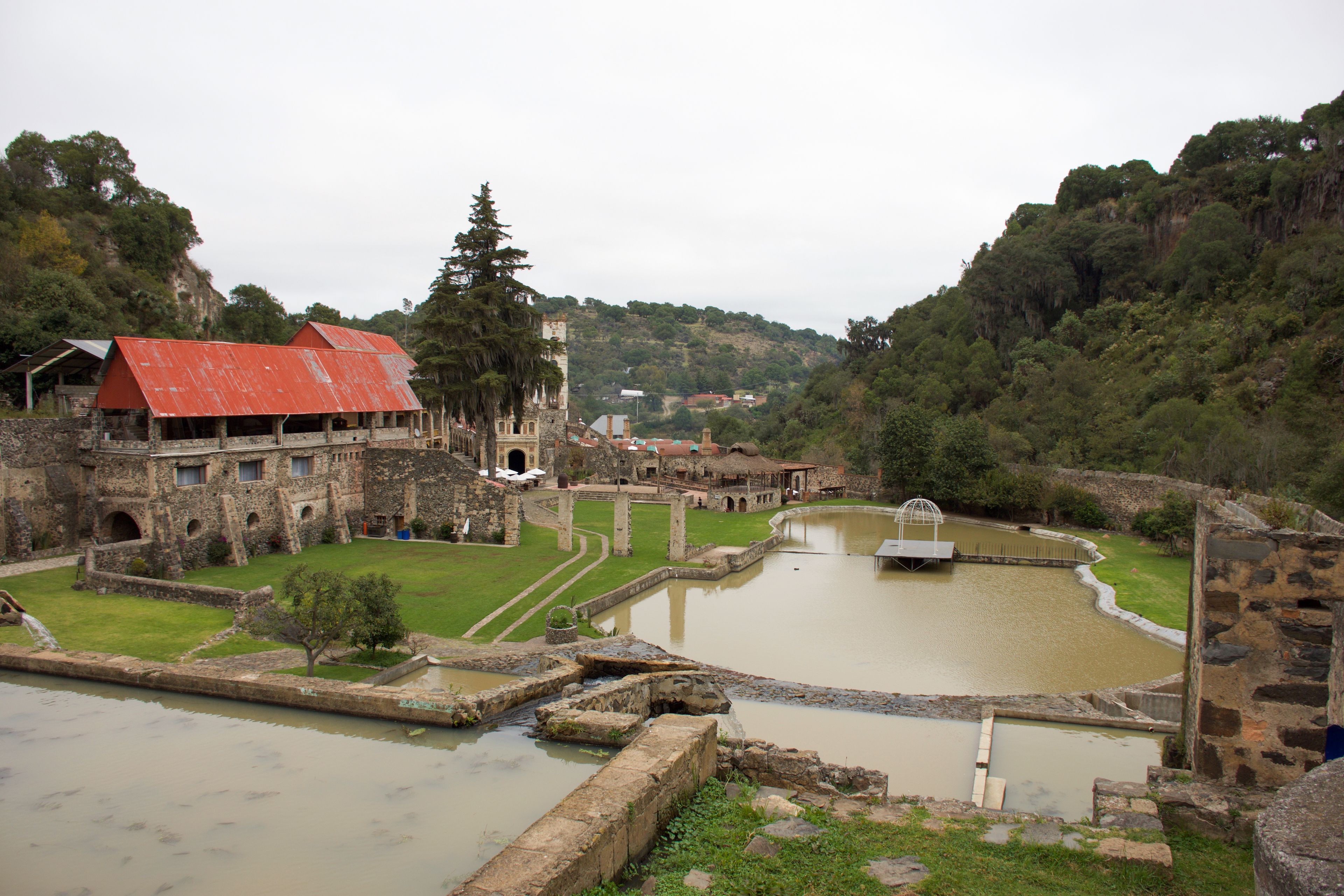 An ancient fortress with a moat, stone walls, and a red-roofed building.