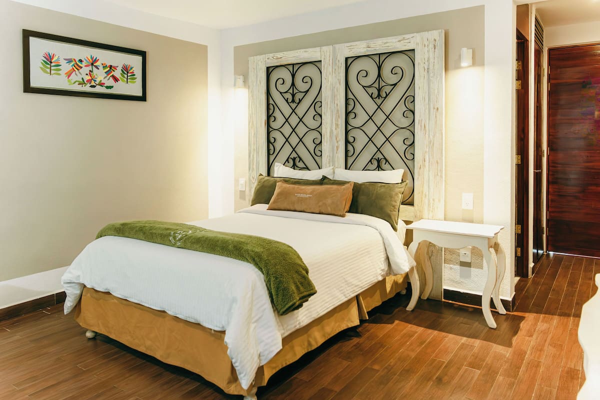 A bedroom with a bed, a bedside table, a wall-mounted artwork, and a door.