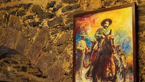 A stone wall with a painting of a person on a horse. There are tables and chairs in the foreground. - Hacienda Santa Maria Regla (San Miguel Regla)